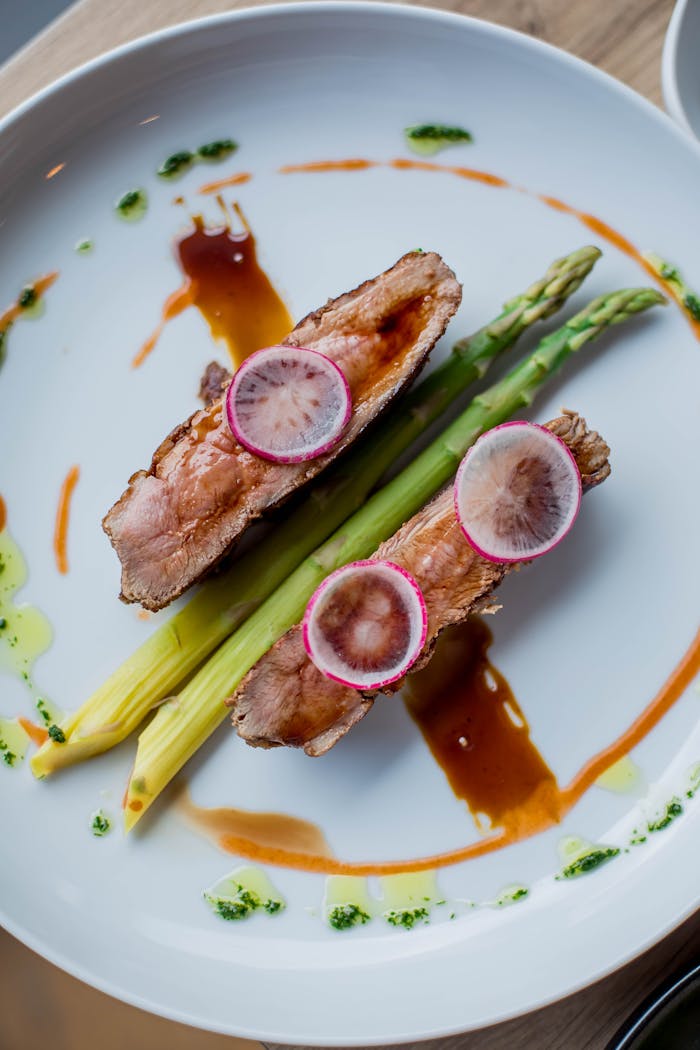 Deliciously plated gourmet meal featuring grilled meat and fresh asparagus with colorful garnishes.